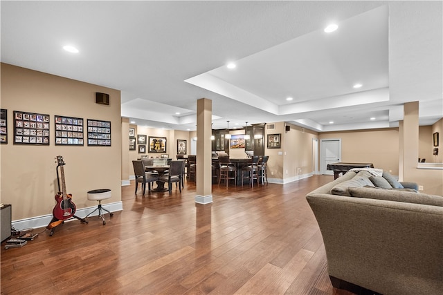 living room with hardwood / wood-style floors, a raised ceiling, and pool table