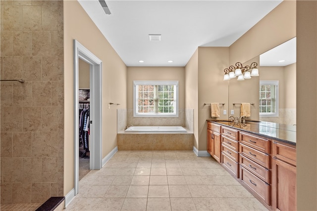 bathroom with vanity, a wealth of natural light, tile patterned floors, and tiled tub