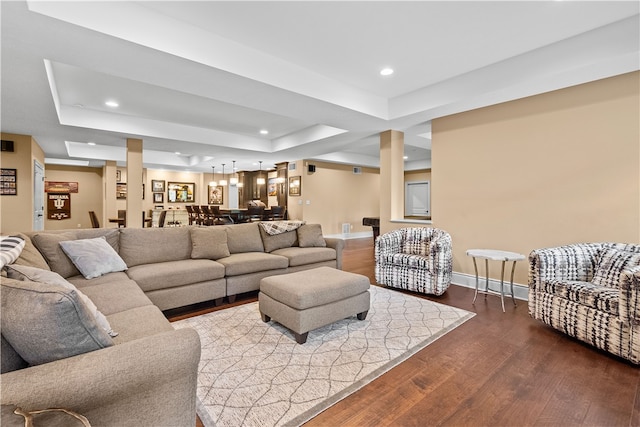 living room with dark hardwood / wood-style flooring and a tray ceiling