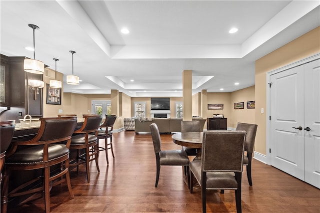 dining area with dark wood-type flooring and a raised ceiling