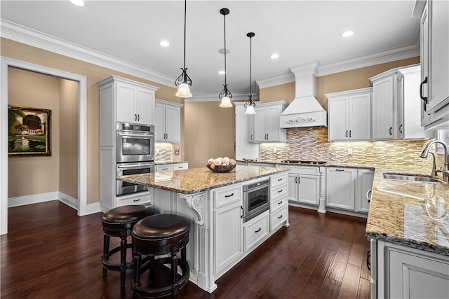 kitchen with premium range hood, a kitchen island, appliances with stainless steel finishes, dark hardwood / wood-style floors, and sink