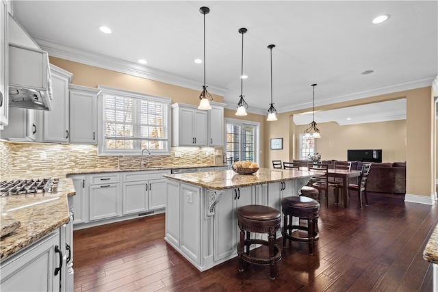 kitchen featuring dark wood-type flooring, a kitchen island, a wealth of natural light, and white cabinets