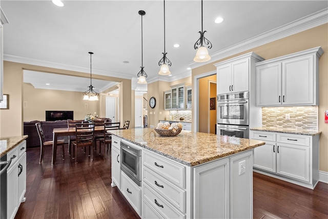 kitchen with stainless steel appliances, dark hardwood / wood-style flooring, hanging light fixtures, a kitchen island, and white cabinetry