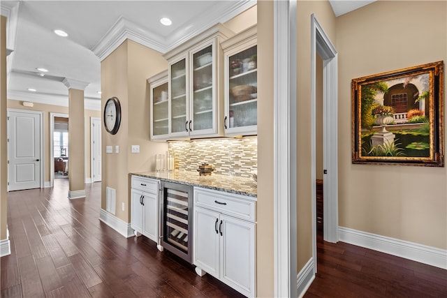 bar with white cabinetry, light stone countertops, decorative columns, dark wood-type flooring, and beverage cooler