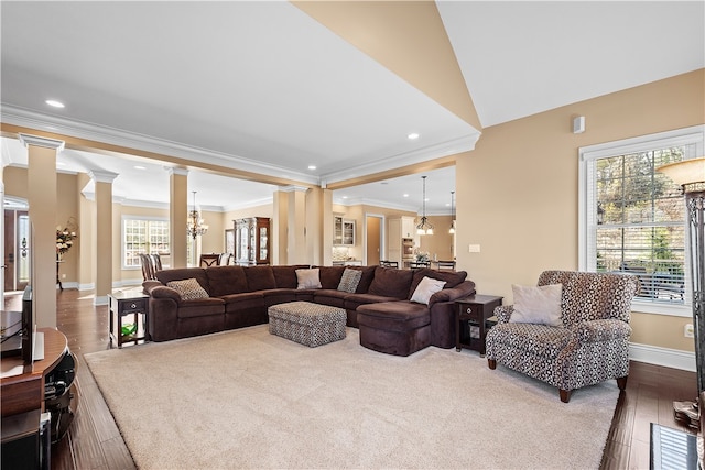 living room featuring ornamental molding, hardwood / wood-style floors, a chandelier, ornate columns, and vaulted ceiling