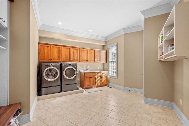 washroom with light tile patterned flooring, crown molding, washer and clothes dryer, cabinets, and sink