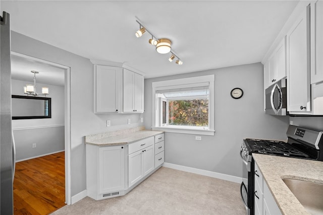 kitchen featuring white cabinets, light wood-type flooring, appliances with stainless steel finishes, and hanging light fixtures