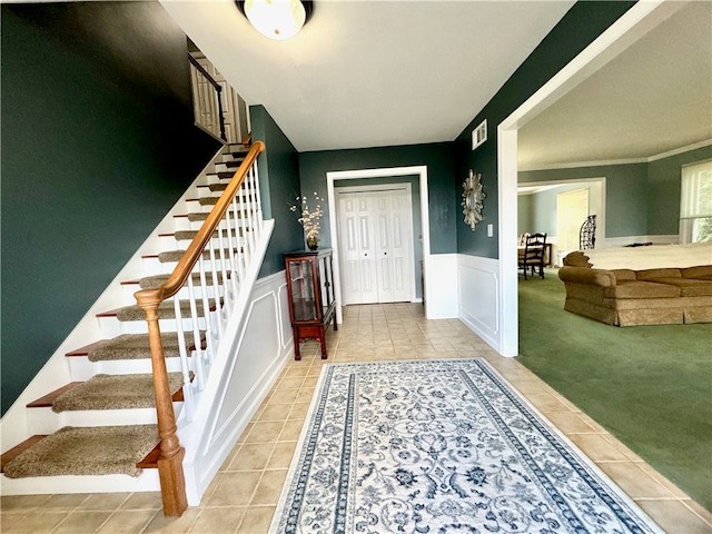 foyer entrance featuring light colored carpet and crown molding