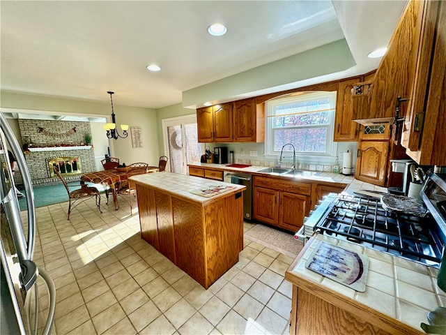 kitchen with stainless steel appliances, tile countertops, light tile patterned floors, decorative light fixtures, and a center island