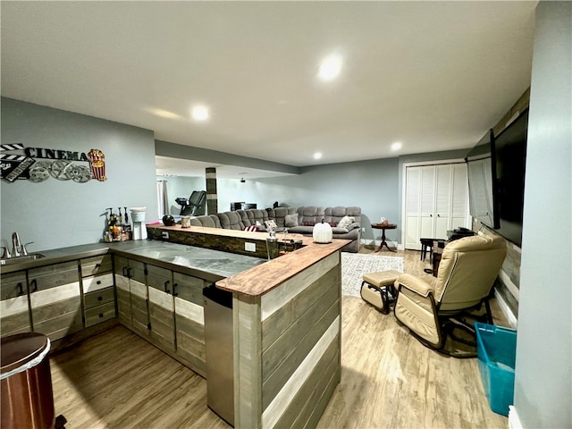 kitchen with light wood-type flooring, kitchen peninsula, and sink