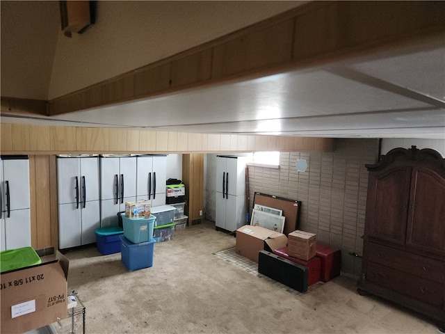 basement with light carpet, white fridge, and brick wall