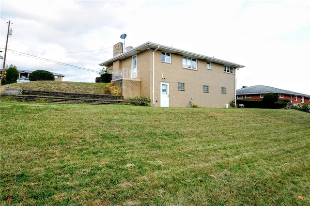 rear view of house featuring a yard and a balcony