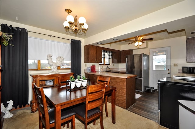 carpeted dining area featuring sink and ceiling fan with notable chandelier