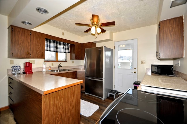 kitchen featuring dark hardwood / wood-style flooring, kitchen peninsula, a textured ceiling, sink, and stainless steel refrigerator