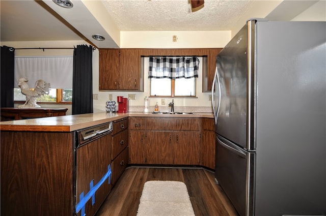 kitchen featuring kitchen peninsula, a textured ceiling, sink, dark hardwood / wood-style floors, and stainless steel fridge