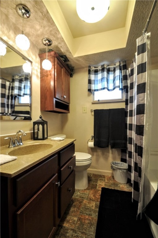 bathroom with toilet, vanity, walk in shower, and a raised ceiling