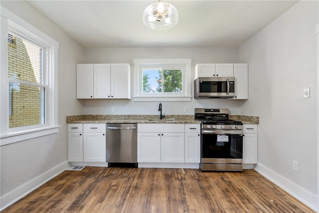 kitchen featuring light stone countertops, stainless steel appliances, sink, white cabinets, and dark hardwood / wood-style floors