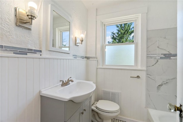 bathroom with tiled shower, vanity, and toilet