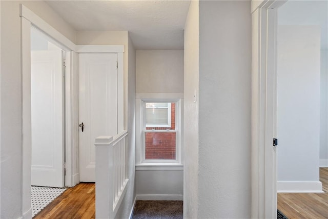 hall with a textured ceiling and light wood-type flooring