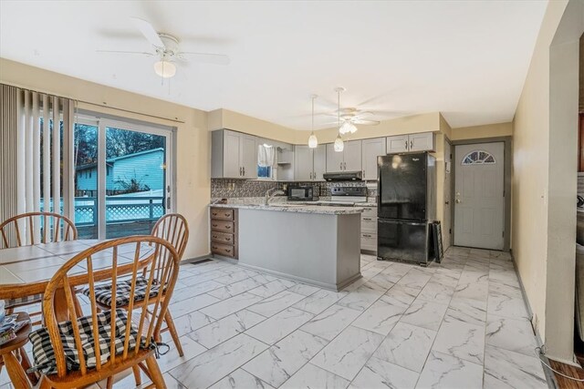 kitchen featuring kitchen peninsula, refrigerator, light stone countertops, gray cabinets, and decorative backsplash