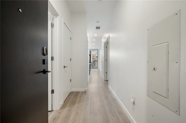 corridor featuring electric panel and light hardwood / wood-style flooring