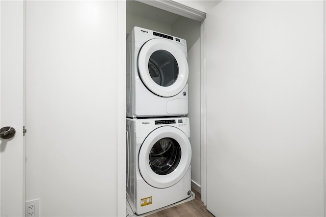 washroom featuring hardwood / wood-style flooring and stacked washer and clothes dryer