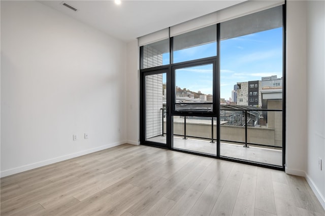 unfurnished room featuring expansive windows and light hardwood / wood-style flooring