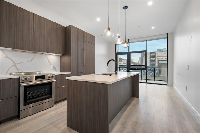 kitchen with a center island with sink, sink, tasteful backsplash, light wood-type flooring, and electric range