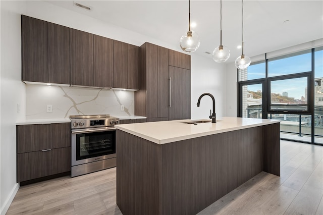 kitchen featuring tasteful backsplash, light wood-type flooring, stainless steel electric range oven, pendant lighting, and sink