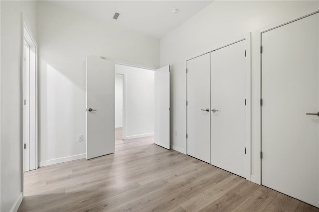 unfurnished bedroom with light hardwood / wood-style flooring and two closets