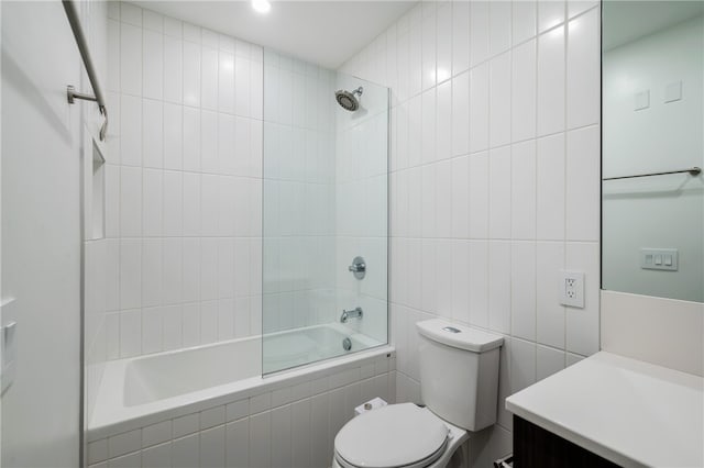 full bathroom featuring toilet, vanity, tiled shower / bath, and tile walls