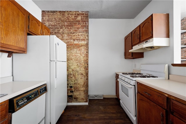 kitchen with white appliances, dark hardwood / wood-style floors, a textured ceiling, and brick wall