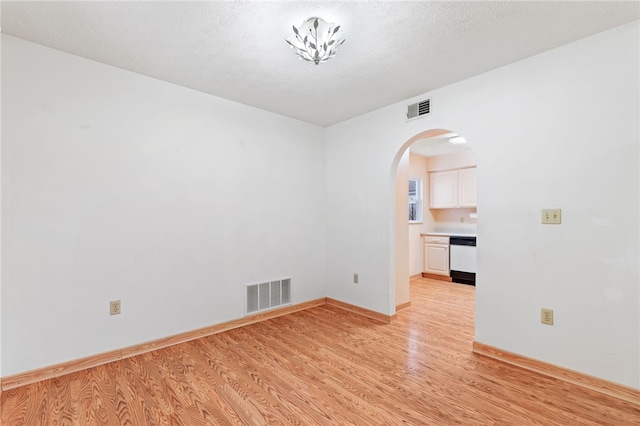 unfurnished room with a textured ceiling and light hardwood / wood-style floors