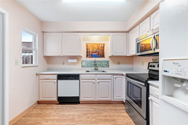 kitchen with white cabinets, light hardwood / wood-style floors, stainless steel appliances, and sink