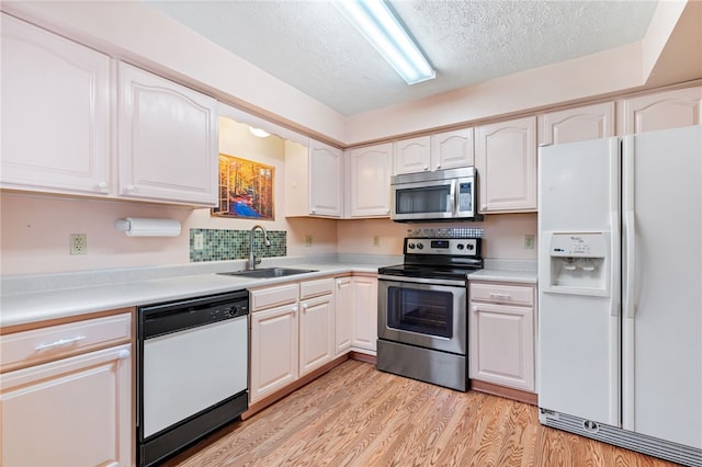 kitchen featuring white cabinetry, sink, appliances with stainless steel finishes, a textured ceiling, and light wood-type flooring