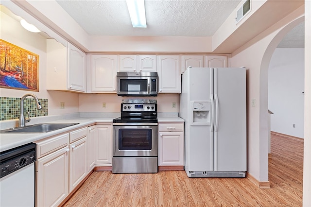 kitchen featuring stainless steel appliances, a textured ceiling, sink, and white cabinetry