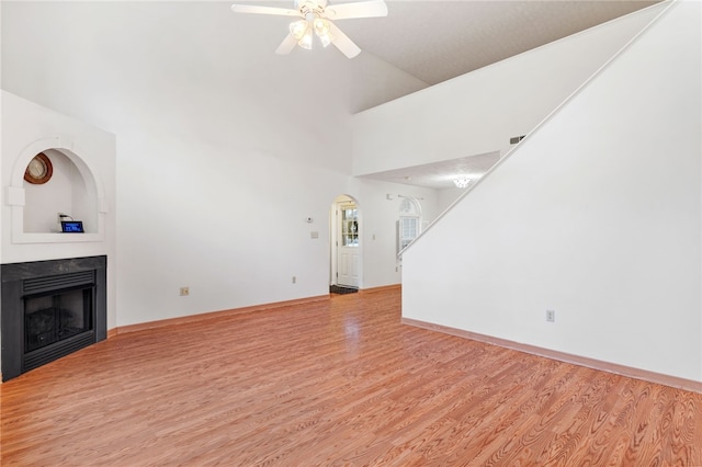 unfurnished living room featuring high vaulted ceiling, light wood-type flooring, and ceiling fan