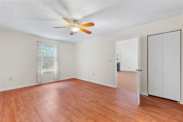 interior space featuring a textured ceiling, light wood-type flooring, and ceiling fan