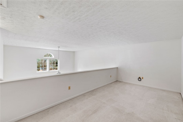 carpeted empty room featuring a textured ceiling