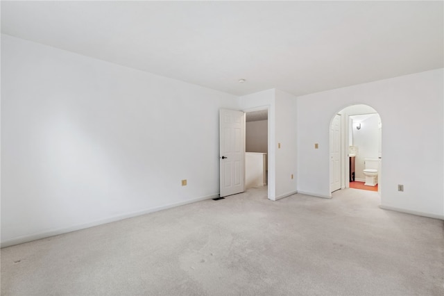 unfurnished bedroom featuring connected bathroom and light carpet