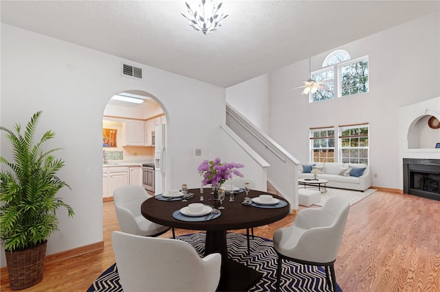 dining area featuring a textured ceiling, a fireplace, light hardwood / wood-style flooring, and ceiling fan