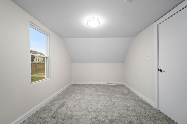 additional living space featuring light carpet and vaulted ceiling