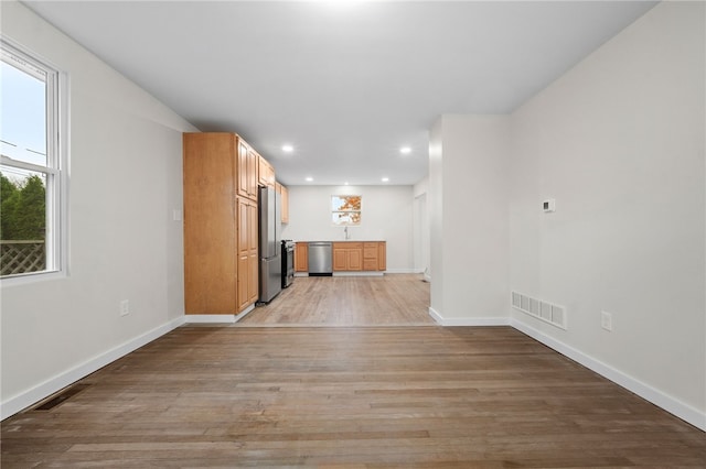 unfurnished living room featuring sink and light hardwood / wood-style flooring