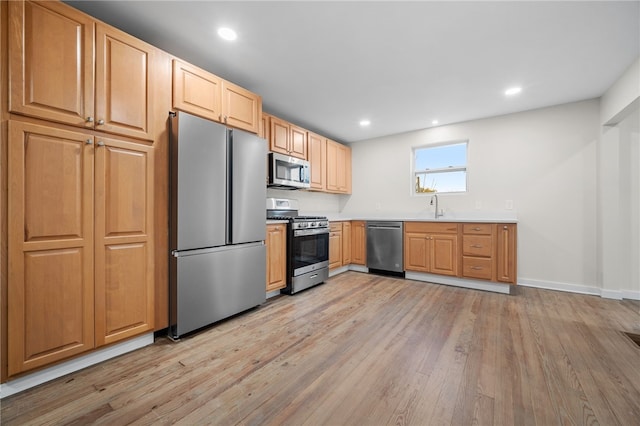 kitchen featuring light wood-type flooring, appliances with stainless steel finishes, and sink