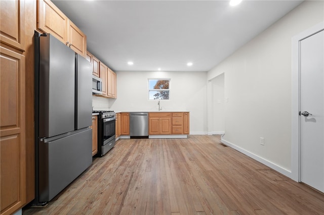 kitchen featuring light brown cabinets, stainless steel appliances, sink, and light hardwood / wood-style flooring