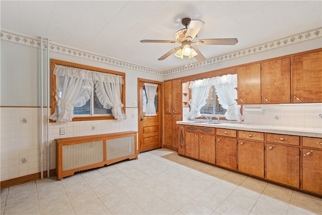 kitchen with radiator, sink, light tile patterned floors, and ceiling fan