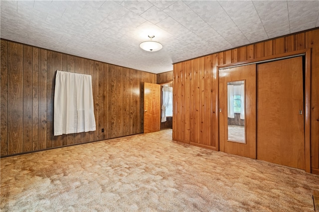 unfurnished bedroom with wood walls, a closet, and carpet floors