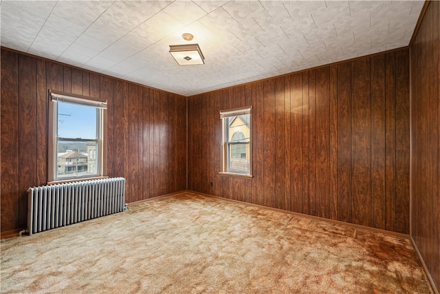 carpeted spare room with radiator and wooden walls