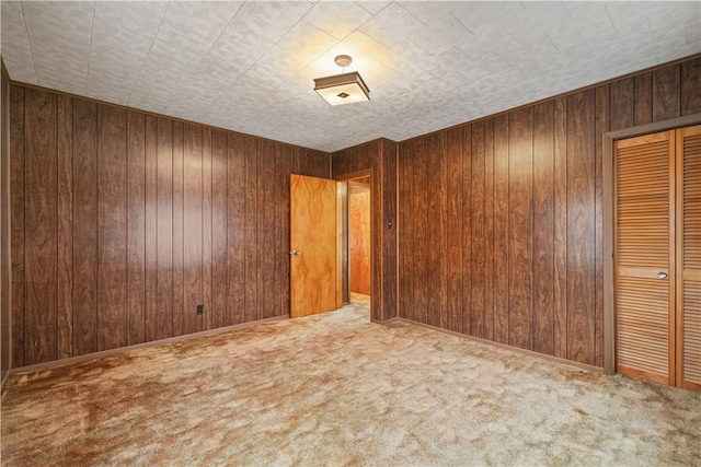 carpeted empty room featuring wood walls