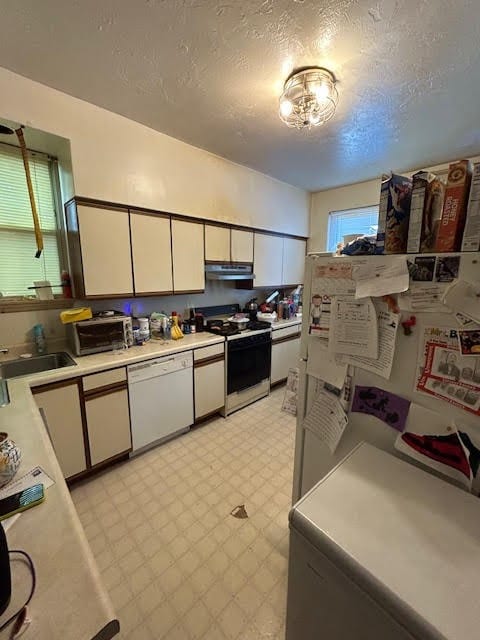 kitchen with white appliances, white cabinetry, sink, and a textured ceiling